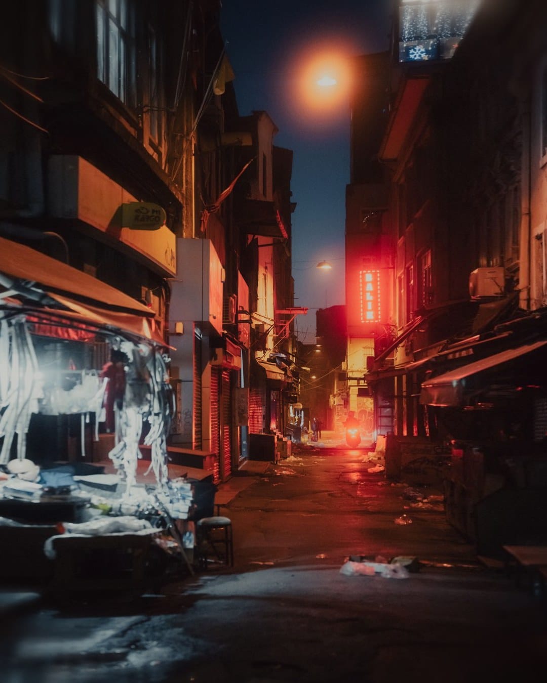 A narrow alley at dusk with a warm streetlight